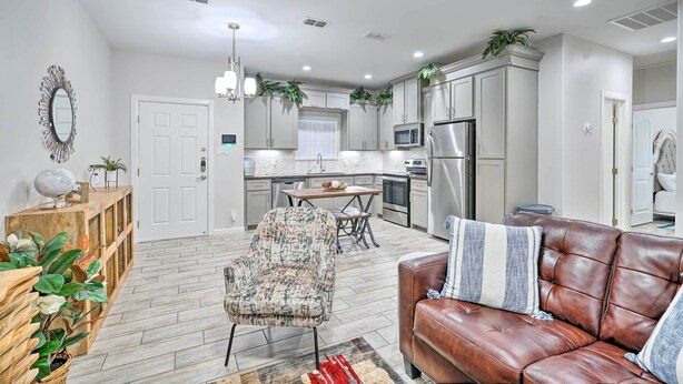 A modern kitchen with white cabinets, a dining table, and a built-in microwave.