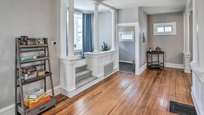 A hallway with wooden flooring, a white columned staircase, and a small table with a plant.