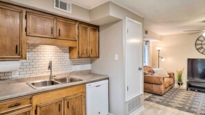 A compact kitchen with wooden cabinets, a white dishwasher, and a tiled backsplash. - Cozy Ruston Townhome < 1 Mi to Louisiana Tech (Ruston)