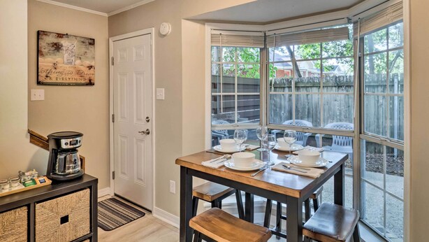 A dining area with a table set for four, a coffee maker on a console table, and a view of a backyard through a large window. - Cozy Ruston Townhome < 1 Mi to Louisiana Tech (Ruston)