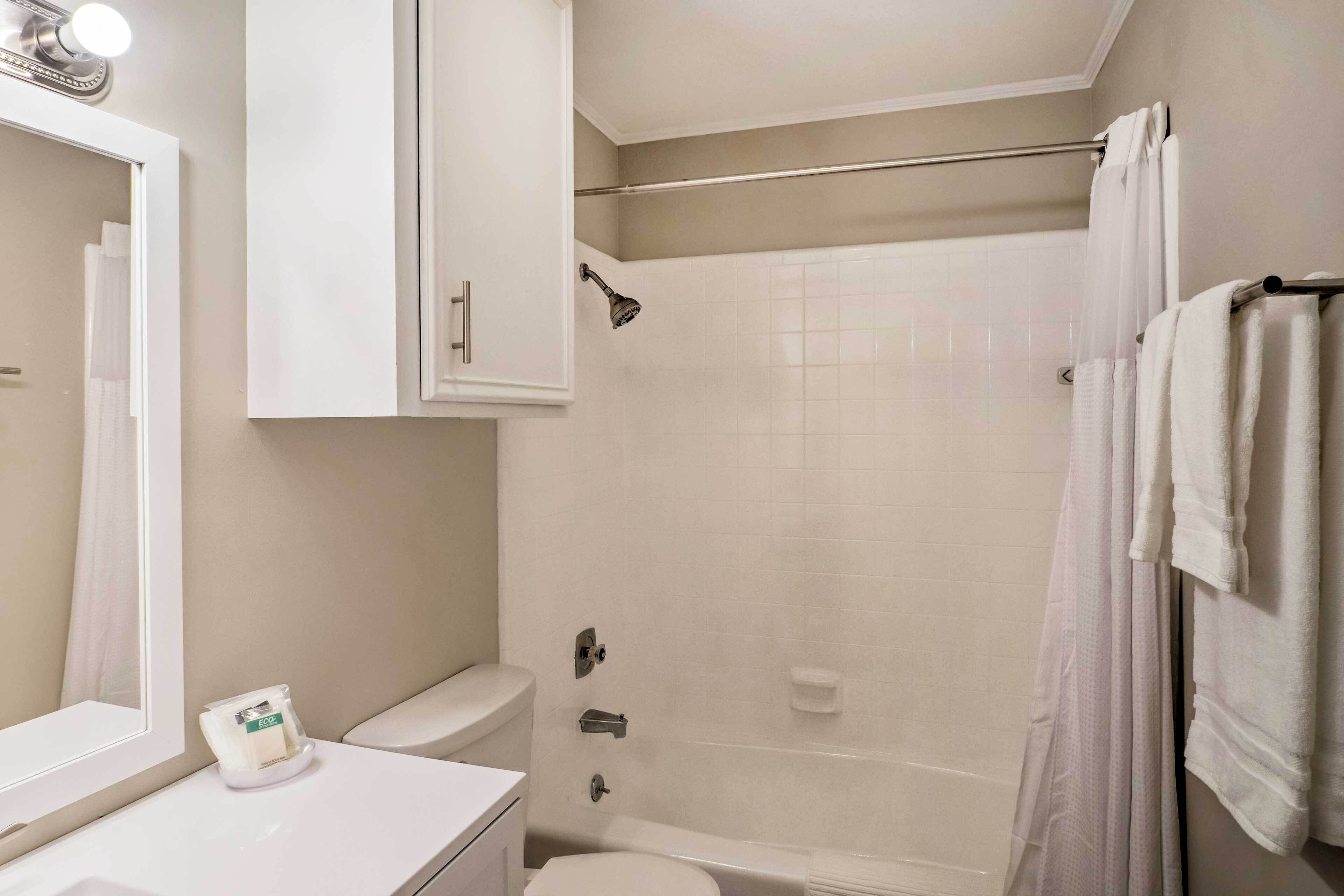A bathroom with a white sink, toilet, and shower area.