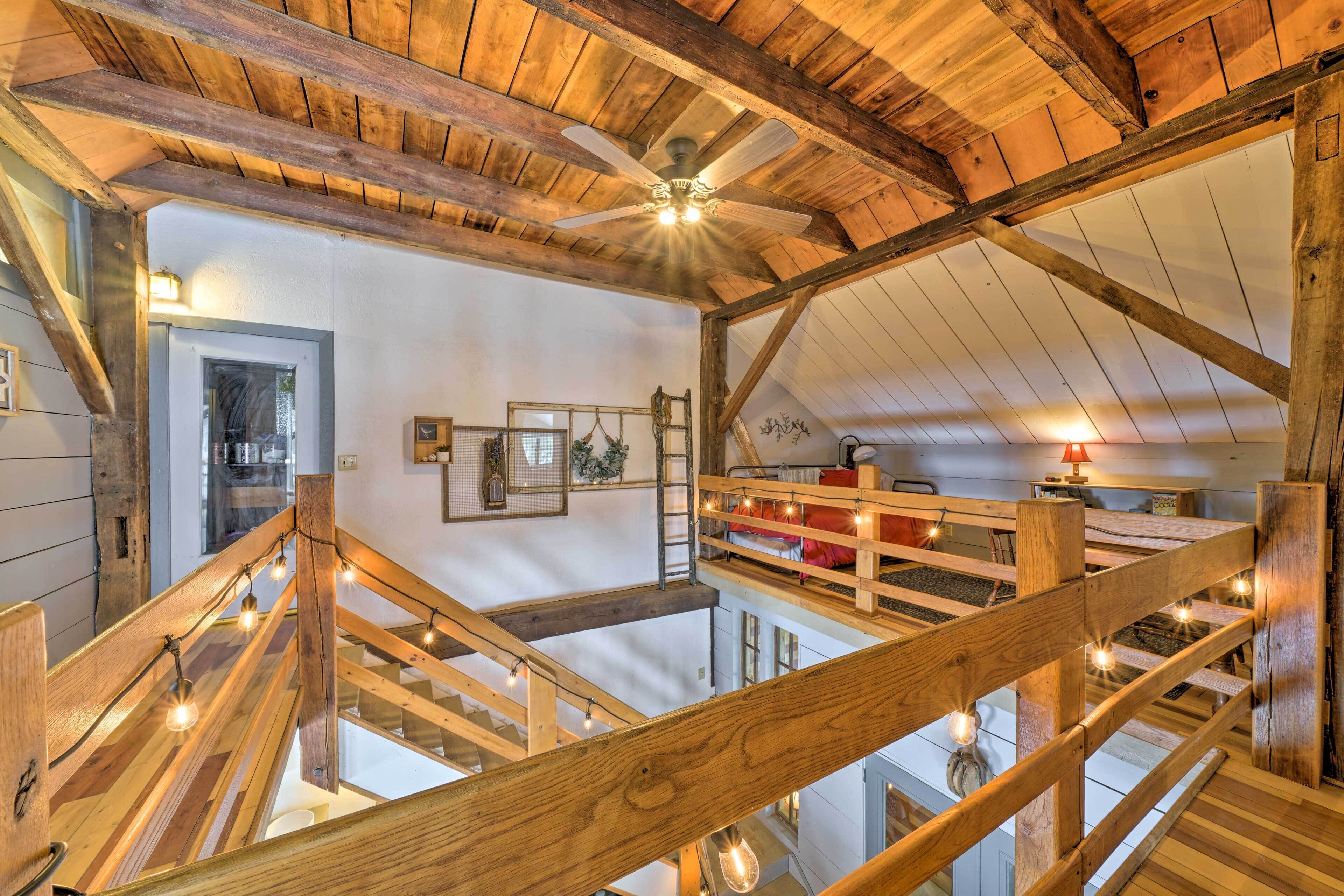 A wooden staircase with string lights, a ceiling fan, and a view of the upper floor.