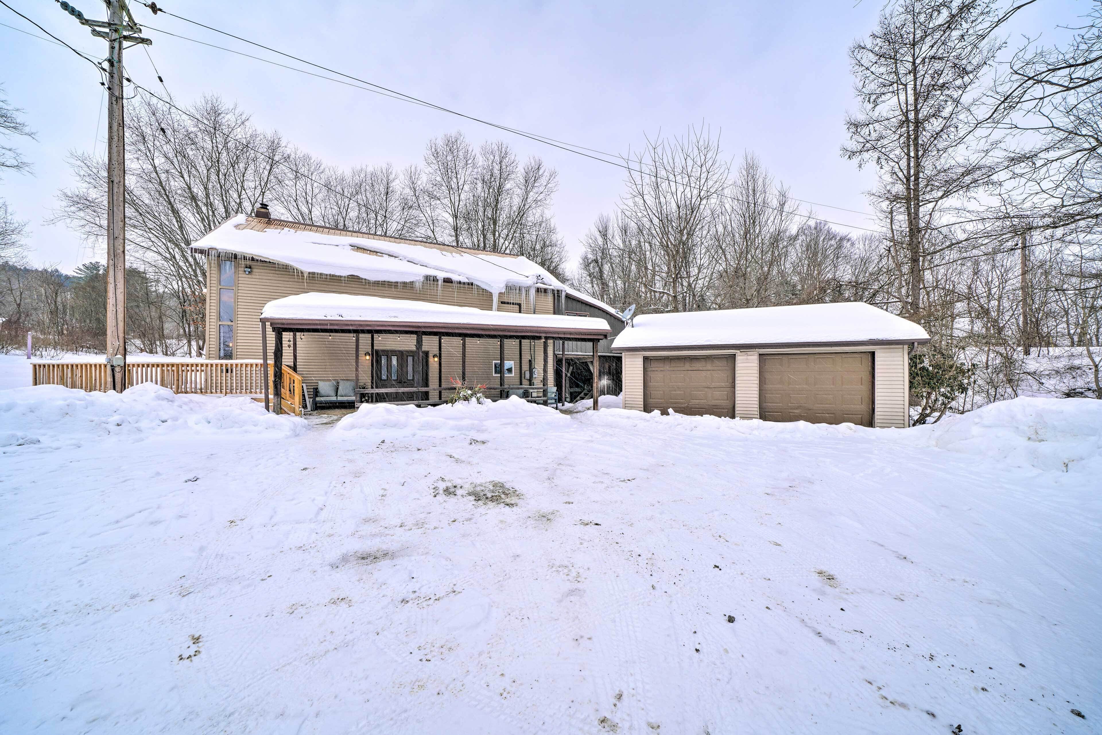 A two-story house with a covered porch and a garage, surrounded by snow.