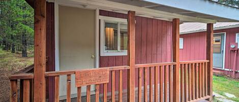 Eine Holzveranda mit einem Schild, auf dem 'GUEST HOUSE' steht, und einer Tür, die zu einem Gebäude mit roter Fassade führt.