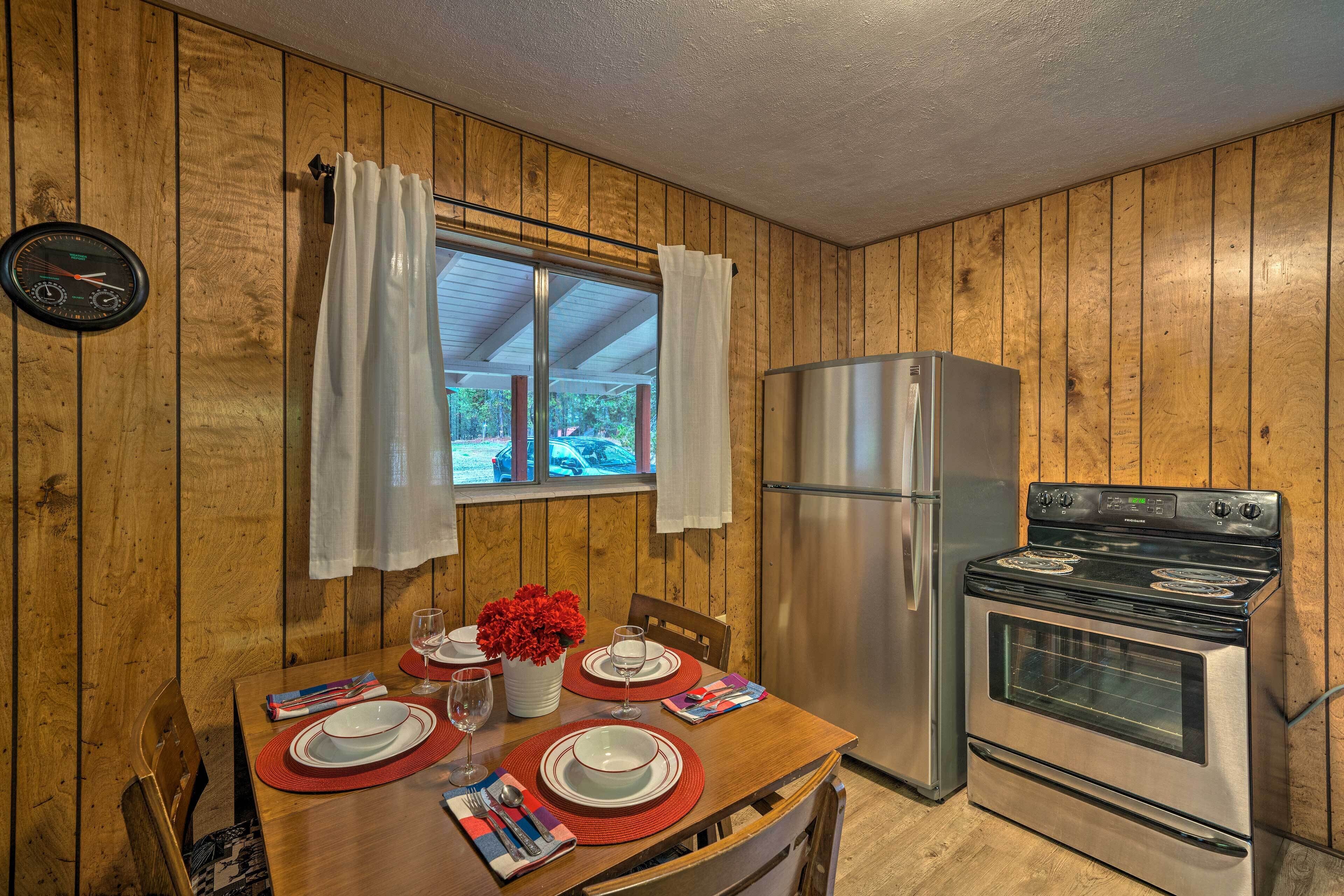Une cuisine aux murs lambrissés, avec une table à manger pour deux personnes, un réfrigérateur et une cuisinière.