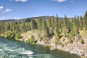 A river flowing through a forested area with a mountain in the background. - The Overlook Gem: Stunning Views & Serenity Awaits (Nine Mile Falls)