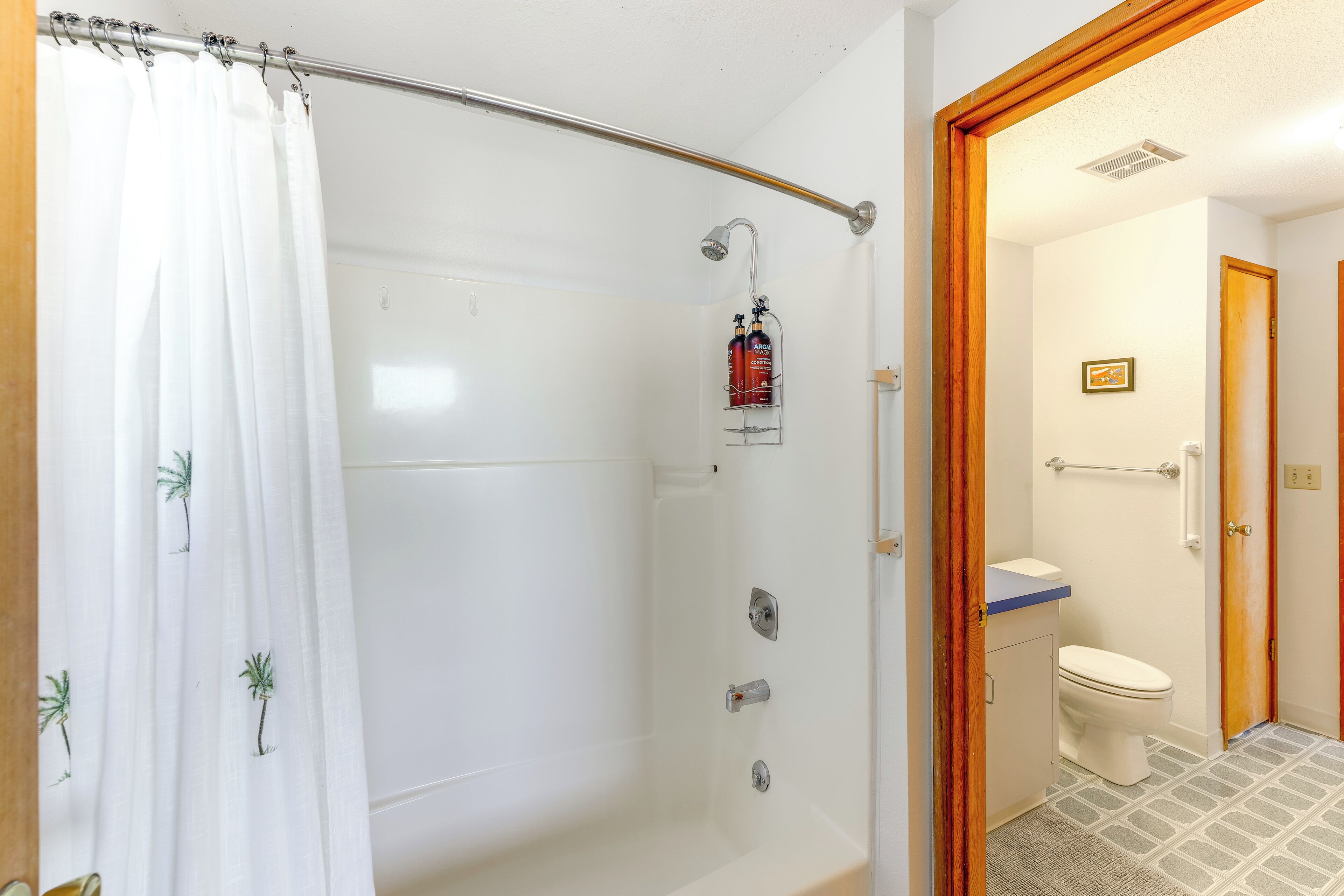 Et badeværelse med bruser, toilet og et lille håndvaskområde.