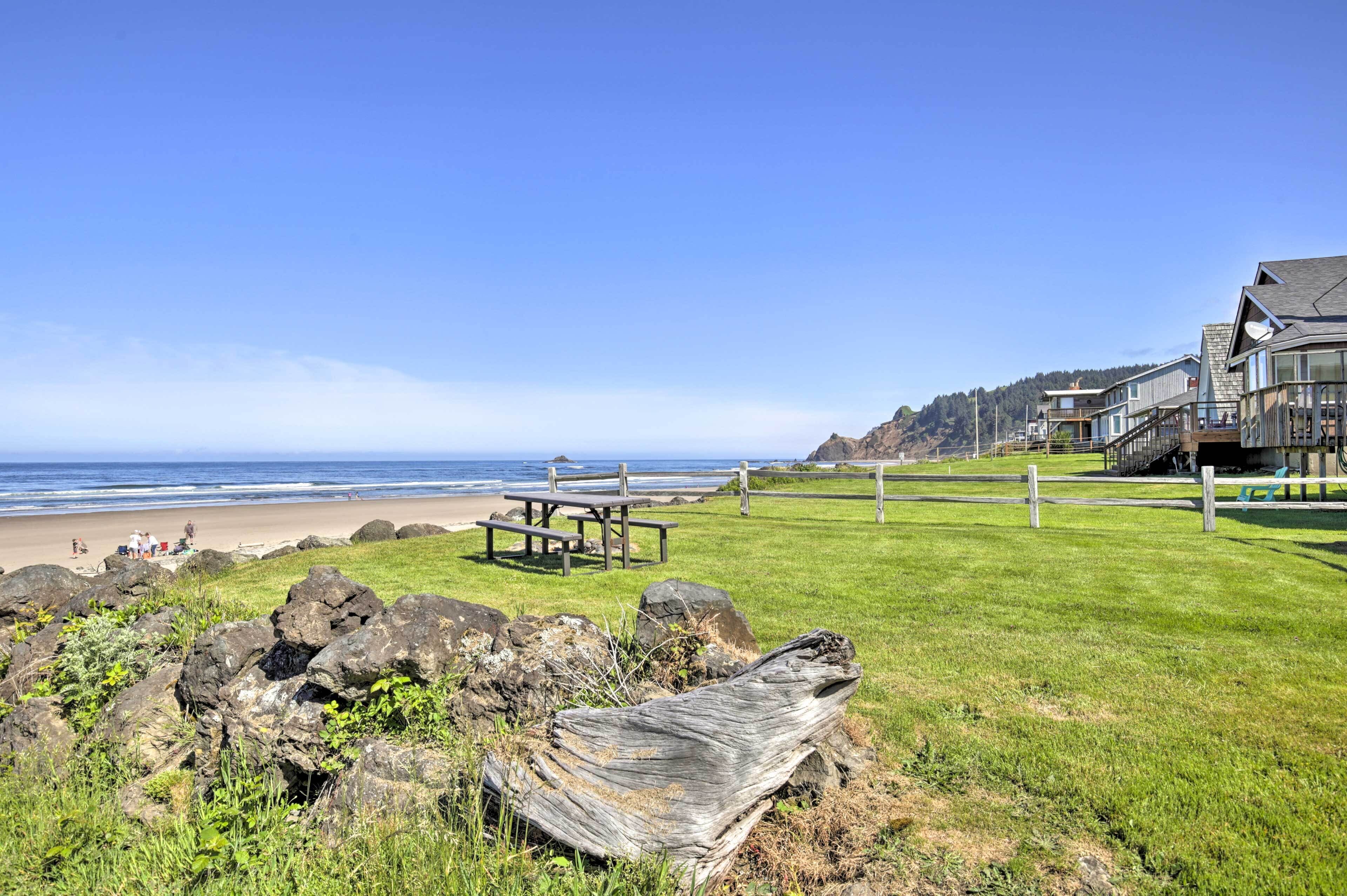 Une vue côtière avec une plage, un premier plan rocheux et une table de pique-nique en bois.