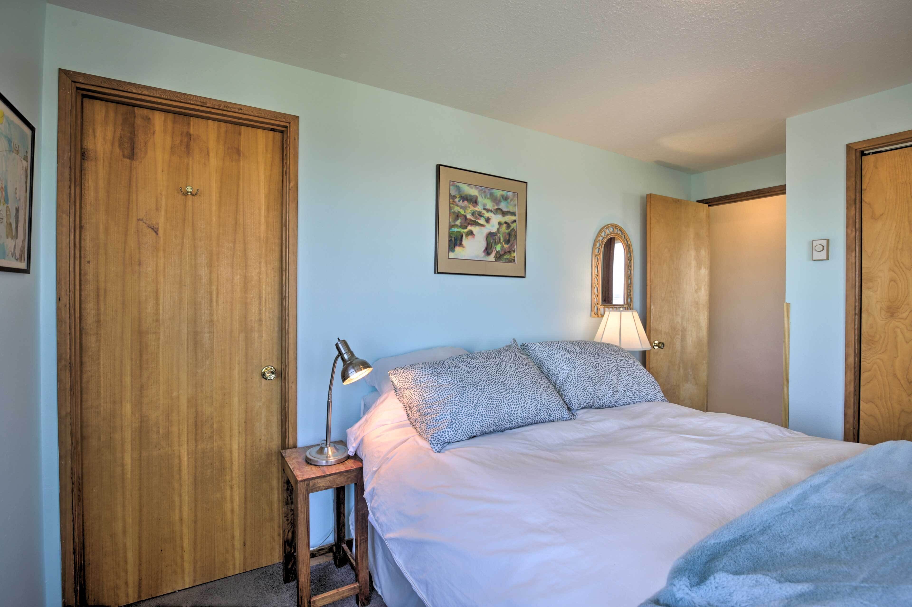 Une chambre à coucher avec un lit, deux lampes de chevet, un tableau encadré au mur et des portes en bois.