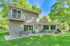 Una casa de dos pisos con un patio, mobiliario exterior y una parrilla.