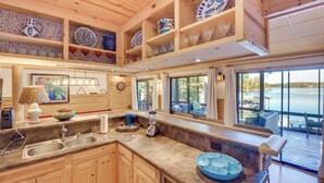 A spacious kitchen with wooden cabinets, a granite countertop, and a view of the lake through large windows. - Beautiful Lake Keowee Home w/ Boat Dock & Fire Pit (Seneca)