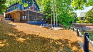 A modern building with a glass facade, outdoor seating area, and a flag. - Beautiful Lake Keowee Home w/ Boat Dock & Fire Pit (Seneca)