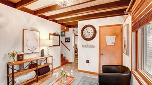 A cozy living room with a wooden bench, a fireplace, and a large clock on the wall. - Private Hot Tub: Cabin 1 Mi to Beech Mountain! (Banner Elk)