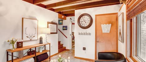 A cozy living room with a wooden bench, a fireplace, and a large clock on the wall.