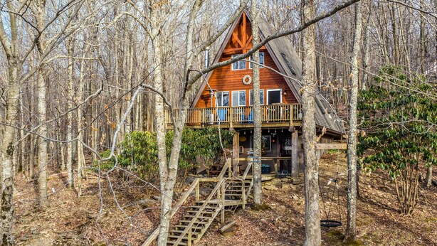 A cabin with a wooden deck and stairs leading to a balcony. - Private Hot Tub: Cabin 1 Mi to Beech Mountain! (Banner Elk)