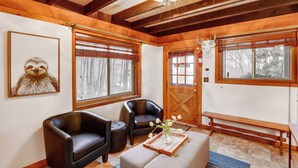 A cozy room with wooden beams, a fireplace, two leather chairs, a bench, and a framed artwork on the wall. - Private Hot Tub: Cabin 1 Mi to Beech Mountain! (Banner Elk)