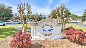 A sign for St. James Marina with a clear view of the surrounding area including parked cars and trees.