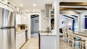 A modern kitchen with stainless steel appliances, a tiled backsplash, and a dining area with wooden chairs and a table. - Home w/ Game Room & Pool: Wichita Falls Retreat (Wichita Falls)