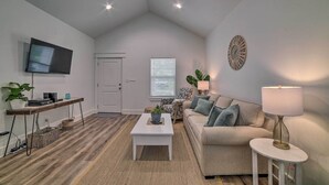 Ein modernes Wohnzimmer mit Flachbildfernseher, einer Couch, einem Couchtisch und einer Lampe.