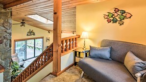 A cozy living room with a gray sofa, a wooden staircase, and a stone wall. - Brocton Escape: Skiing, Snowtubing, Hiking! (Brocton)