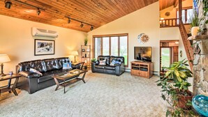 A spacious living room with a high ceiling, leather sofas, a coffee table, and a TV. - Brocton Escape: Skiing, Snowtubing, Hiking! (Brocton)