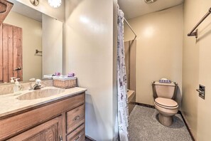 A bathroom with a wooden vanity, a sink, a toilet, and a shower curtain. - Primitive Goshen Pine Lodge With Fireplace! (Middlebury)