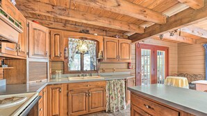 A rustic kitchen with wooden cabinets, a large window, and a sink. - Primitive Goshen Pine Lodge With Fireplace! (Middlebury)