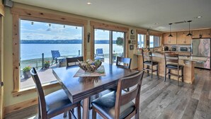 Cucina spaziosa con ampie finestre vista lago, pavimento in legno e isola centrale con posti a sedere.
