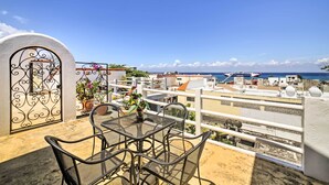 Una terraza en la azotea con una mesa, sillas, un portón decorativo y vistas al mar y edificios.