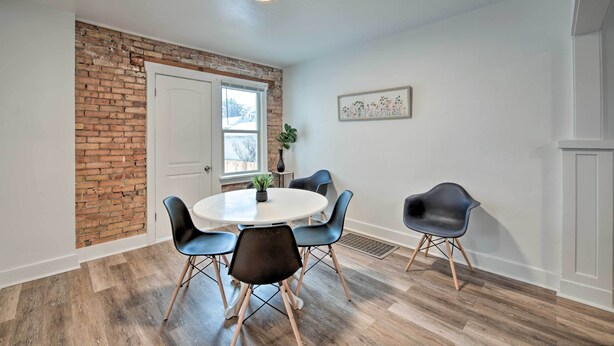 Un coin repas agrémenté d’un mur en briques apparentes, d’une table ronde et de chaises modernes.