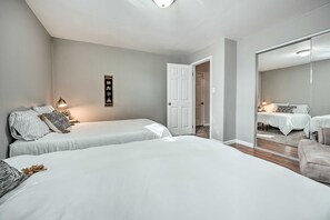 Un dormitorio con dos camas, un espejo grande y una puerta que da a otra habitación.