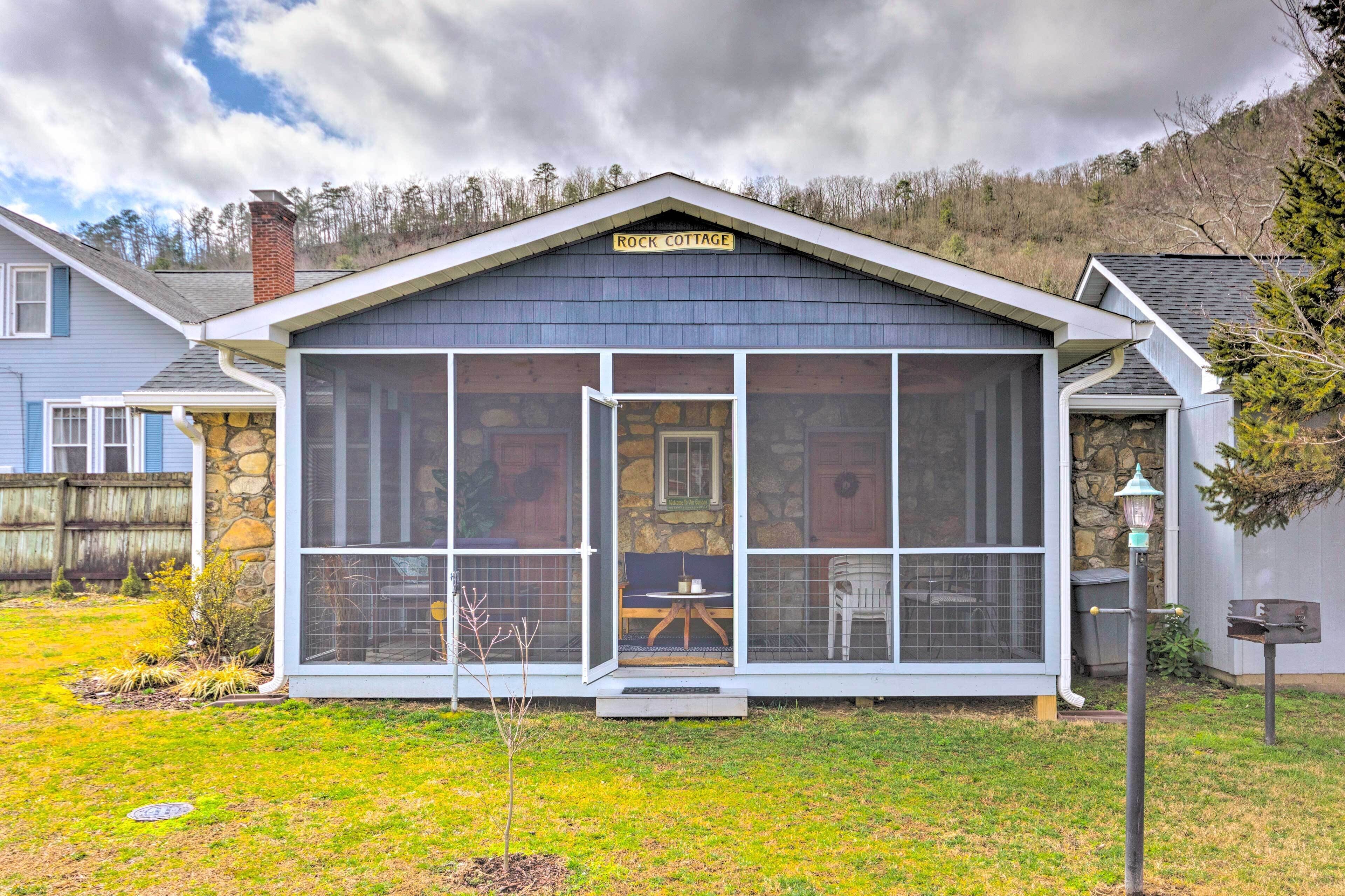 Uma casa com varanda fechada, chaminé de pedra e um letreiro que diz 'Rock Cottage'.