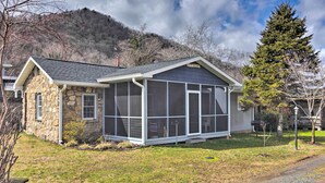 A stone house with a screened porch, a small front yard, and a mountain backdrop. - Screened Porch: 'the Rock Cottage' in Hot Springs (Hot Springs)