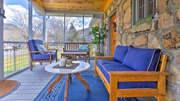 A covered porch with a stone wall, wooden furniture, and a view of the surrounding landscape. - Screened Porch: 'the Rock Cottage' in Hot Springs (Hot Springs)