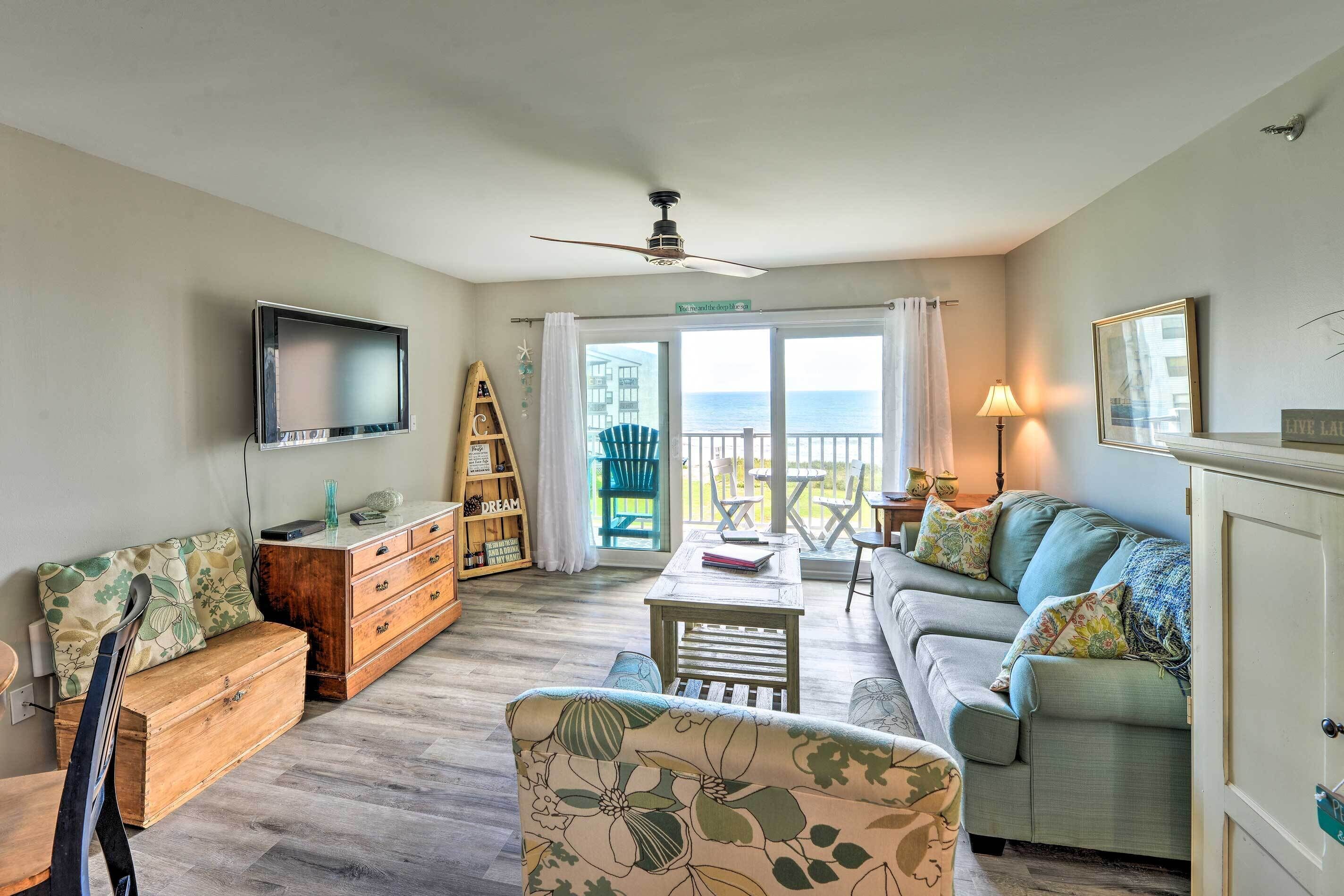 Ein Wohnzimmer mit Sofa, Holzschrank, Fernseher und Balkon mit Blick.