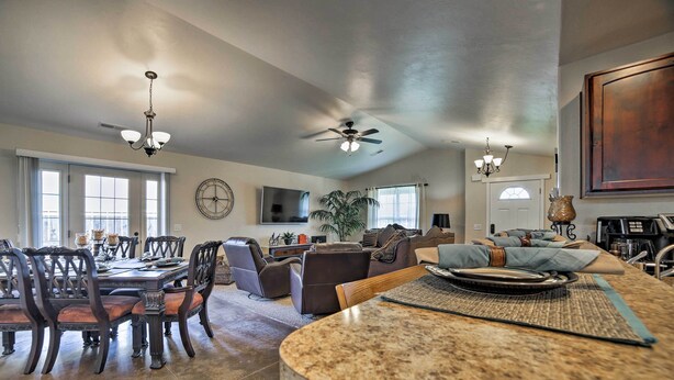 A spacious living area with a dining table, chairs, sofas, and a kitchen island. - Mountain-view Moab Home w/ Pool & Hot Tub Access! (Moab)