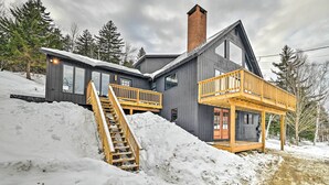Une cabane moderne dotée d’une terrasse en bois, d’un escalier et d’une grande cheminée.