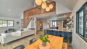Un vaste espace de vie comprenant une table à manger en bois, un canapé et un escalier menant à un niveau supérieur.