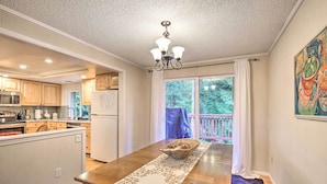 A kitchen with wooden cabinets, a central island, and a dining table with a runner. - Spacious Kent Getaway w/ Yard, Deck + Grill! (Kent)