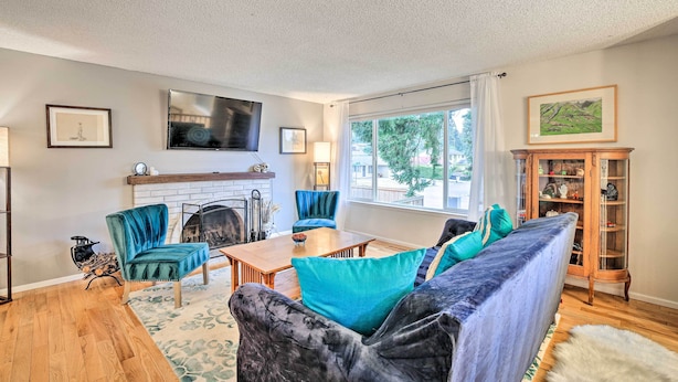 A living room with a fireplace, a sofa, a TV, and a window with a view of trees. - Spacious Kent Getaway w/ Yard, Deck + Grill! (Kent)