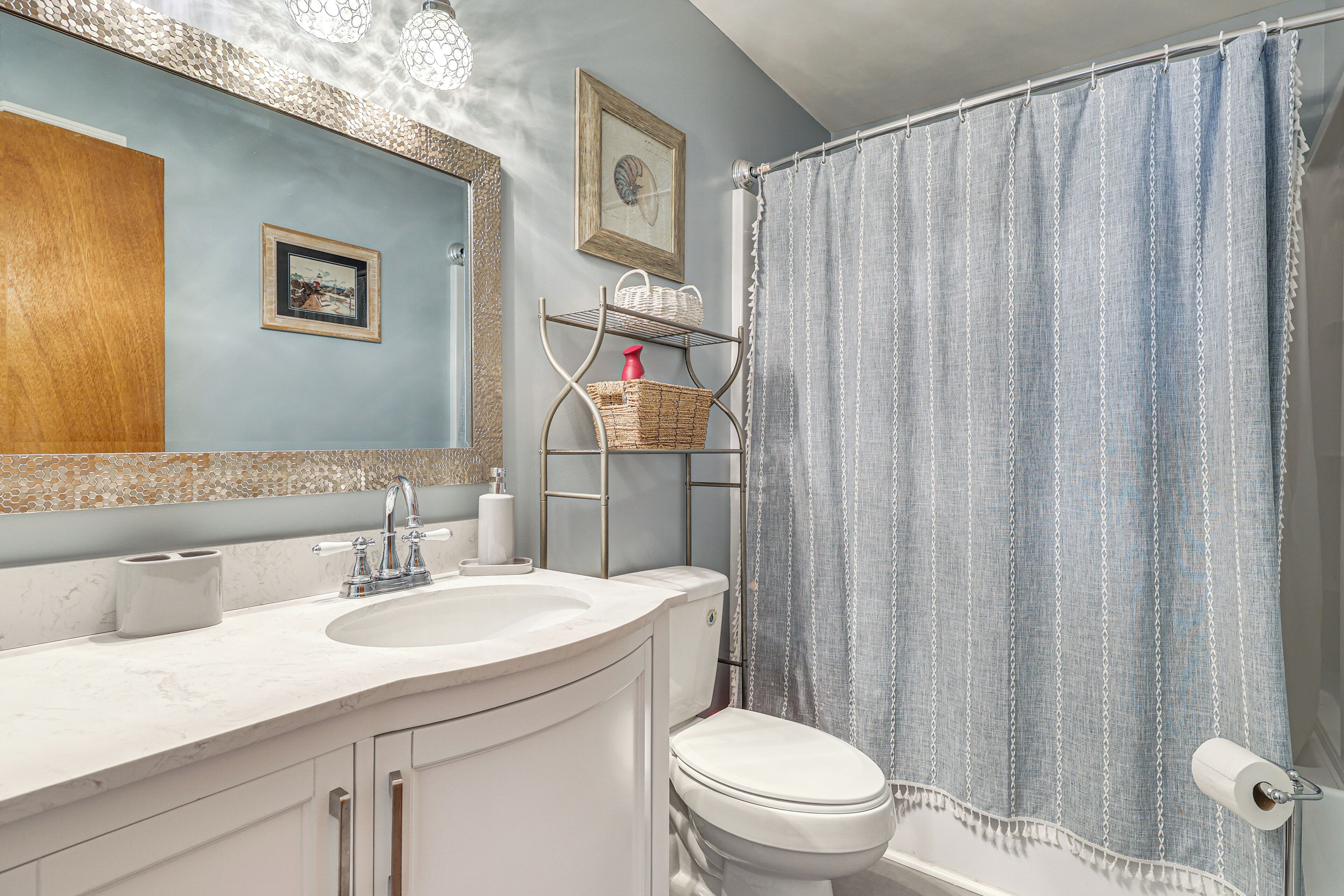 A bathroom with a sink, toilet, and shower curtain.