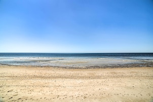 Una playa con cielo despejado y mar tranquilo.