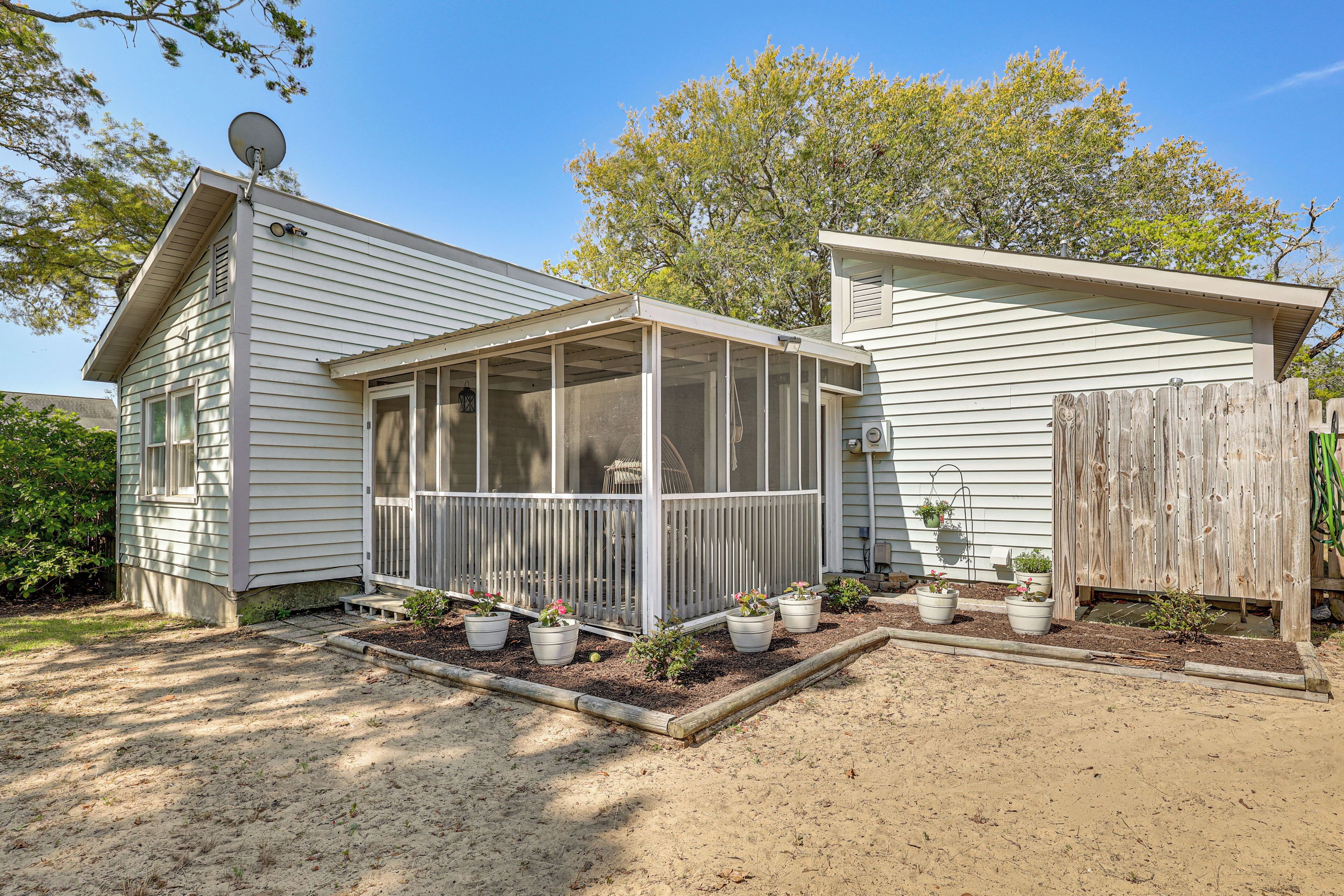 Einbungalow mit überdachter Veranda, Satellitenschüssel und Holzzaun.