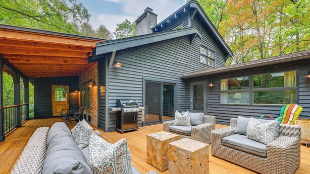 A covered outdoor deck with wicker furniture, a grill, and a wooden table. - Chic Highlands Cabin Retreat w/ Deck + Office! (Highlands)
