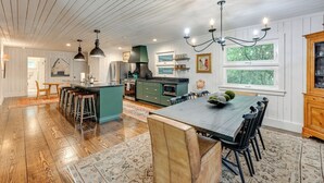 A spacious kitchen with wooden floors, a central island, bar stools, and a dining table with chairs. - Chic Highlands Cabin Retreat w/ Deck + Office! (Highlands)