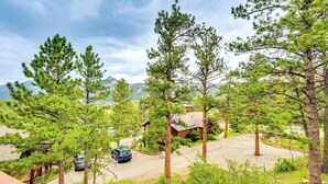 A residential area with a house surrounded by tall pine trees, a driveway, and a parked car. - Estes Park Condo w/ Deck & Views ~ 3 Miles to Rmnp (Estes Park)