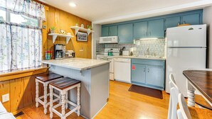 A kitchen with wooden cabinets, a microwave, a refrigerator, and a window with curtains. - Estes Park Condo w/ Deck & Views ~ 3 Miles to Rmnp (Estes Park)