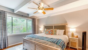 A bedroom with a large bed, a ceiling fan, a nightstand with a lamp, and a window with curtains. - Estes Park Condo w/ Deck & Views ~ 3 Miles to Rmnp (Estes Park)