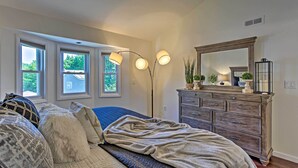 A bedroom with a large bed, a dresser, a mirror, and three windows. - Updated Home w/ Patio Half Mile to West Point (Highland Falls)