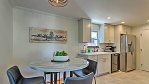 A modern kitchen with a round marble table, black chairs, and a stainless steel refrigerator. - Updated Home w/ Patio Half Mile to West Point (Highland Falls)